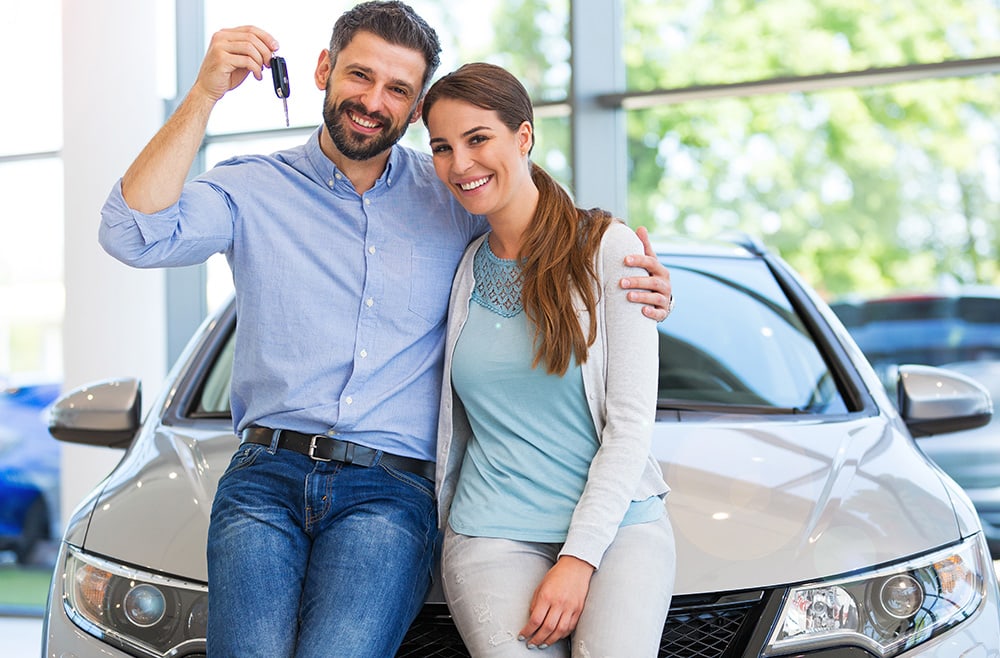 two people holding up the keys to their car thanks to their car loan