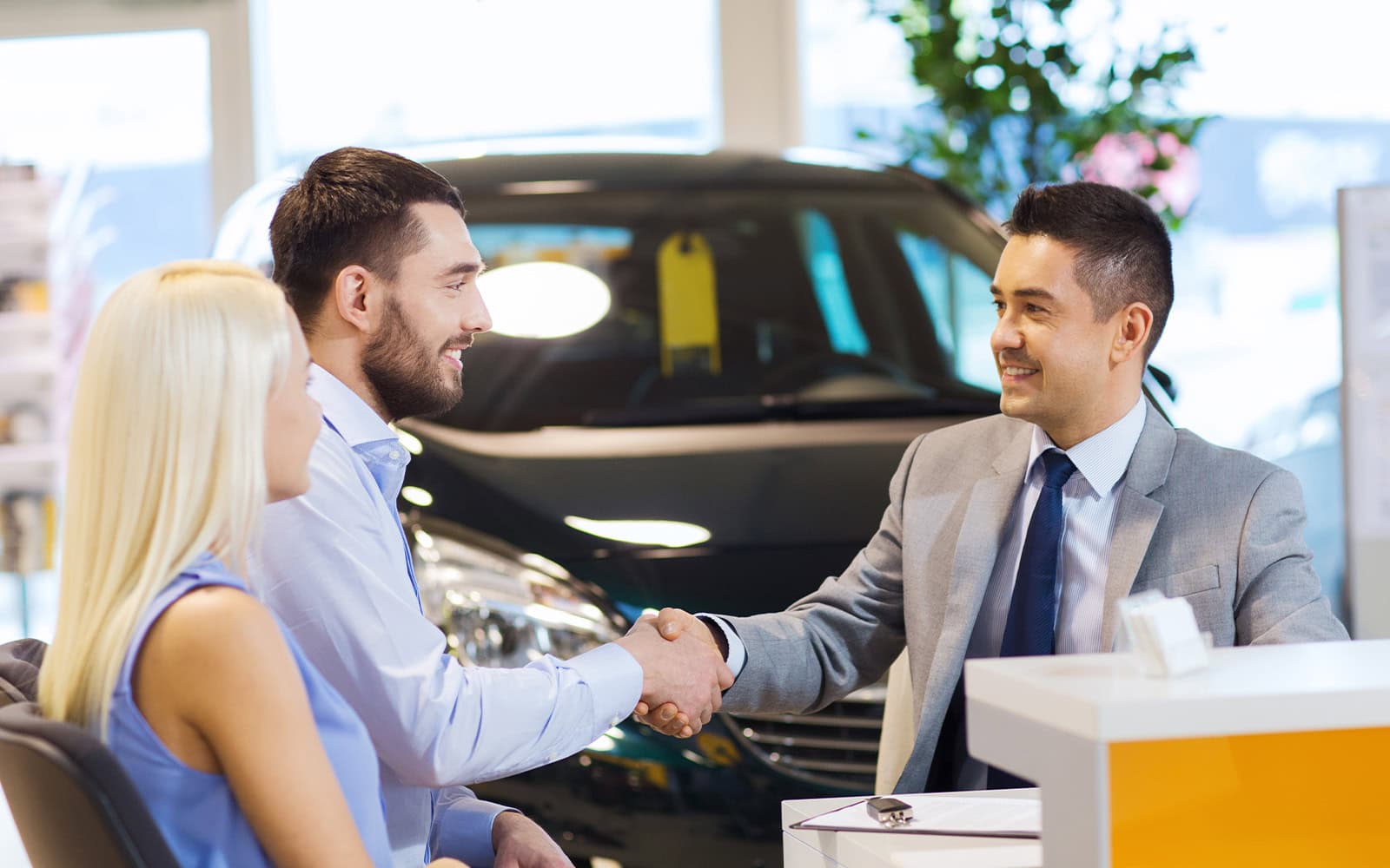 two people shaking hands at a car dealership