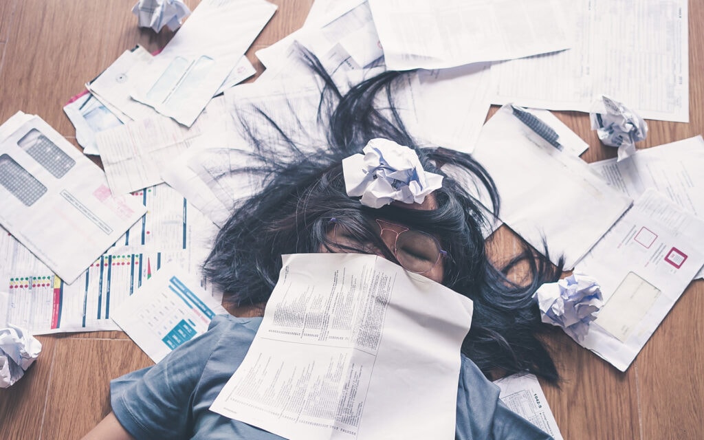a woman lying under a pile of bills