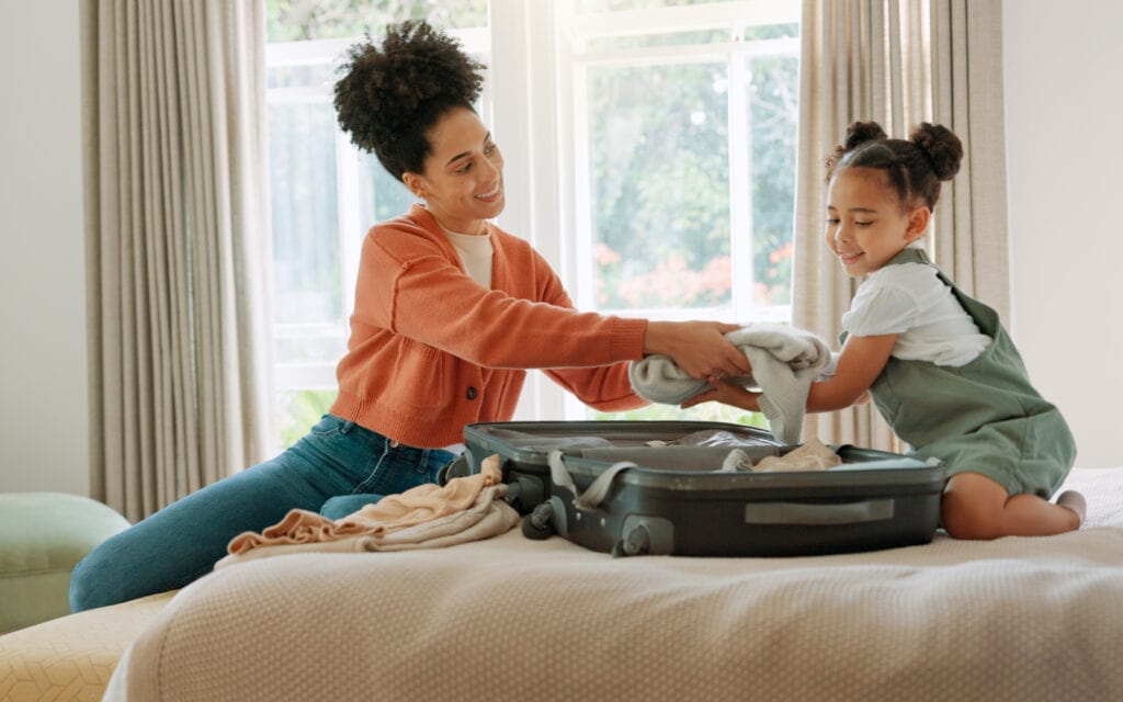 Smiling mum and daughter packing luggage for a family getaway funded by an Auckland Loans.