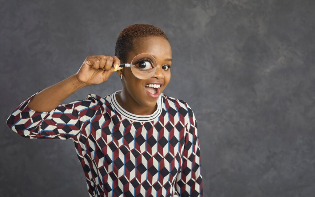 Woman holding magnifying glass up to face